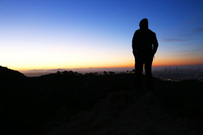 Silhouette of man standing on mountain top over los angeles at sunrise