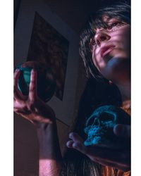 Low angle view of thoughtful woman holding human skull with globe at home