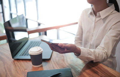 Midsection of man using mobile phone at office