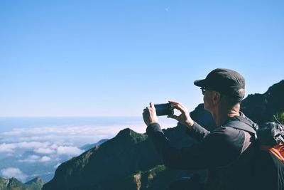 Man photographing against sky