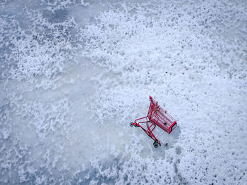 High angle view of red shopping cart on frozen water.