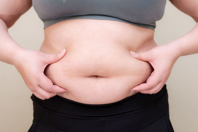 Midsection of woman standing against white background