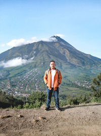 Rear view of man standing on mountain against sky