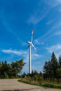 Low angle view of wind turbine against blue sky