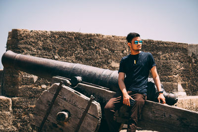 Young man wearing sunglasses standing against clear sky