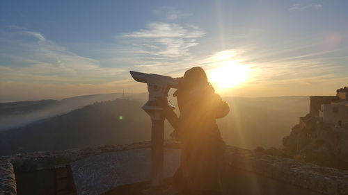 Man standing on mountain against sky during sunset