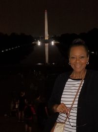 Portrait of a smiling young woman standing at night