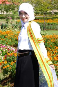 Smiling girl standing by flowering plants