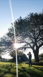 Man standing by tree on field against sky