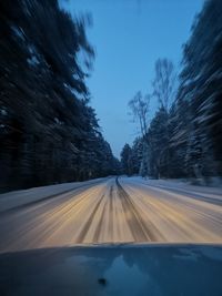 Road amidst trees against sky during winter