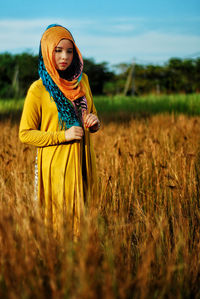 Woman wearing headscarf while standing amidst plants on field
