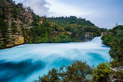 Scenic view of waterfall in forest against sky