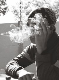 Close-up of young man smoking while sitting outdoors