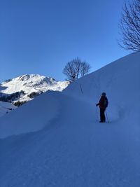 Rear view of person on snowcapped mountain against sky