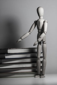 Wooden figurine by books on gray background