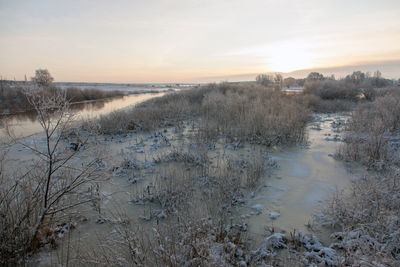 Scenic view of frozen lake against sky during sunset