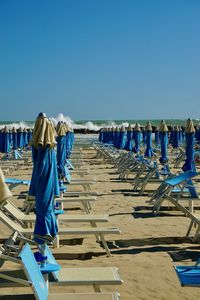 Rear view of woman standing at beach against clear blue sky