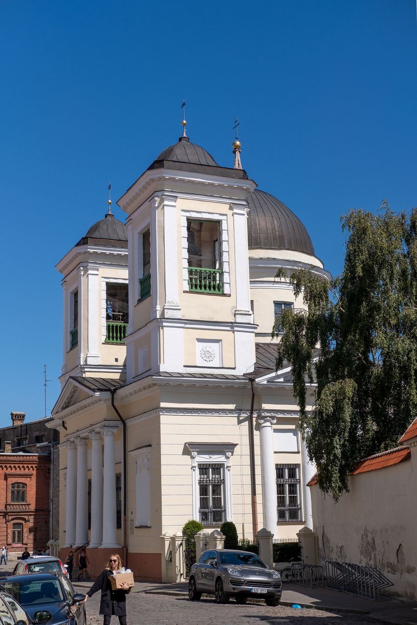 building exterior, built structure, architecture, sky, building, clear sky, nature, city, plant, tree, blue, place of worship, day, incidental people, sunlight, transportation, motor vehicle, mode of transportation, car, religion, outdoors