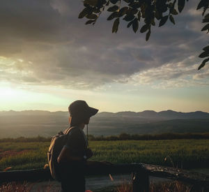 Man standing on field against sky during sunset