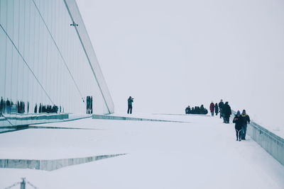 People on snow covered landscape against sky