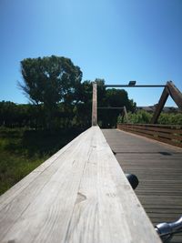 View of wooden bridge against clear blue sky