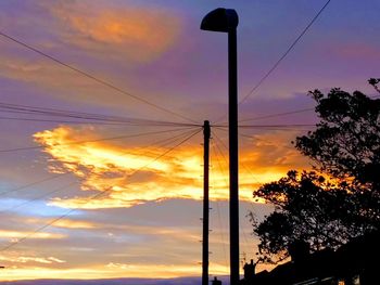 Low angle view of silhouette trees against orange sky