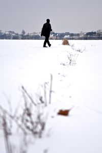 Man walking on snow field against clear sky