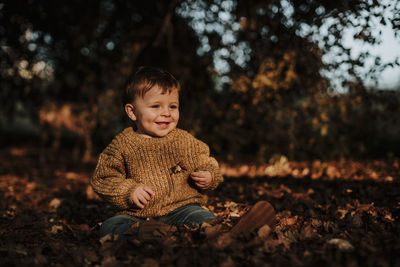 Portrait of cute boy sitting on land