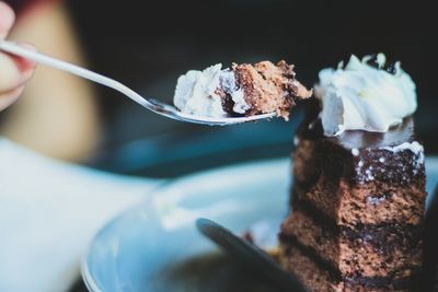 Close-up of person hand holding cake in spoon