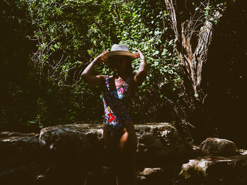 Woman standing on rock against trees