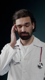 Doctor having headache against black background
