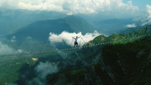 Man on footbridge against mountains