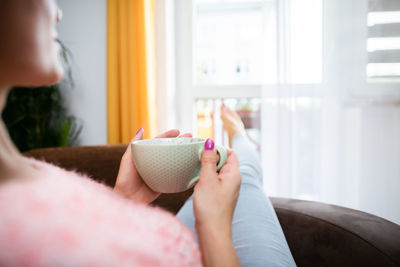 A woman's hand holds a large mug of fresh coffee.