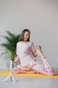 Portrait of young woman sitting against white background