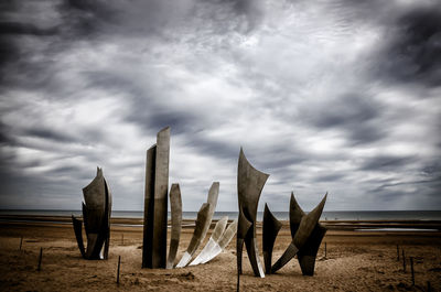 Wooden posts on beach against sky