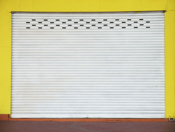 Closed shutter of yellow wall