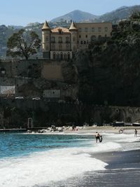 Buildings by sea against trees in city