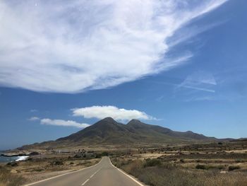 Road leading towards mountains against sky