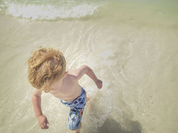 High angle view of shirtless boy running in sea