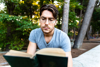 Young man reading book while sitting in park