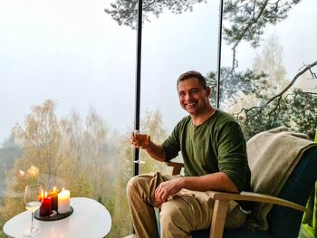 Man sitting in a forest house with a glass of wine