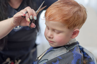 4 year old redhead boy at the barbershop. hairdresser cuts a child's hair