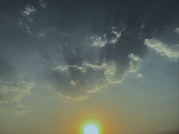 Low angle view of sunlight streaming through clouds