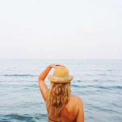 Rear view of woman wearing hat against sea at beach