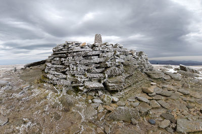 Man-made icy rock formation on mountain summit against sky