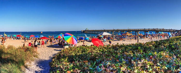 Crowded sands of deerfield beach near the pier with unrecognizable faces in deerfield, florida