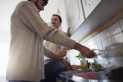 Gay couple talking in kitchen while washing dishes