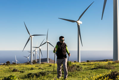 Full length of man walking against wind turbines