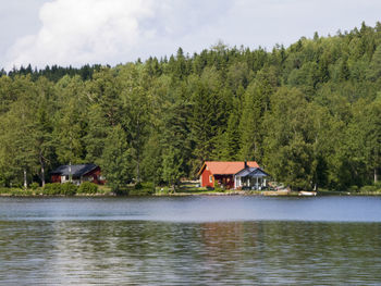 Scenic view of lake by trees and building against sky