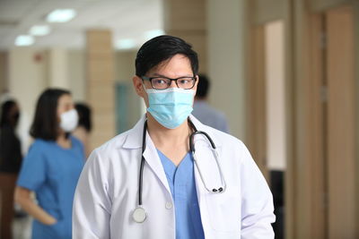 Doctor wearing mask looking away while standing in hospital